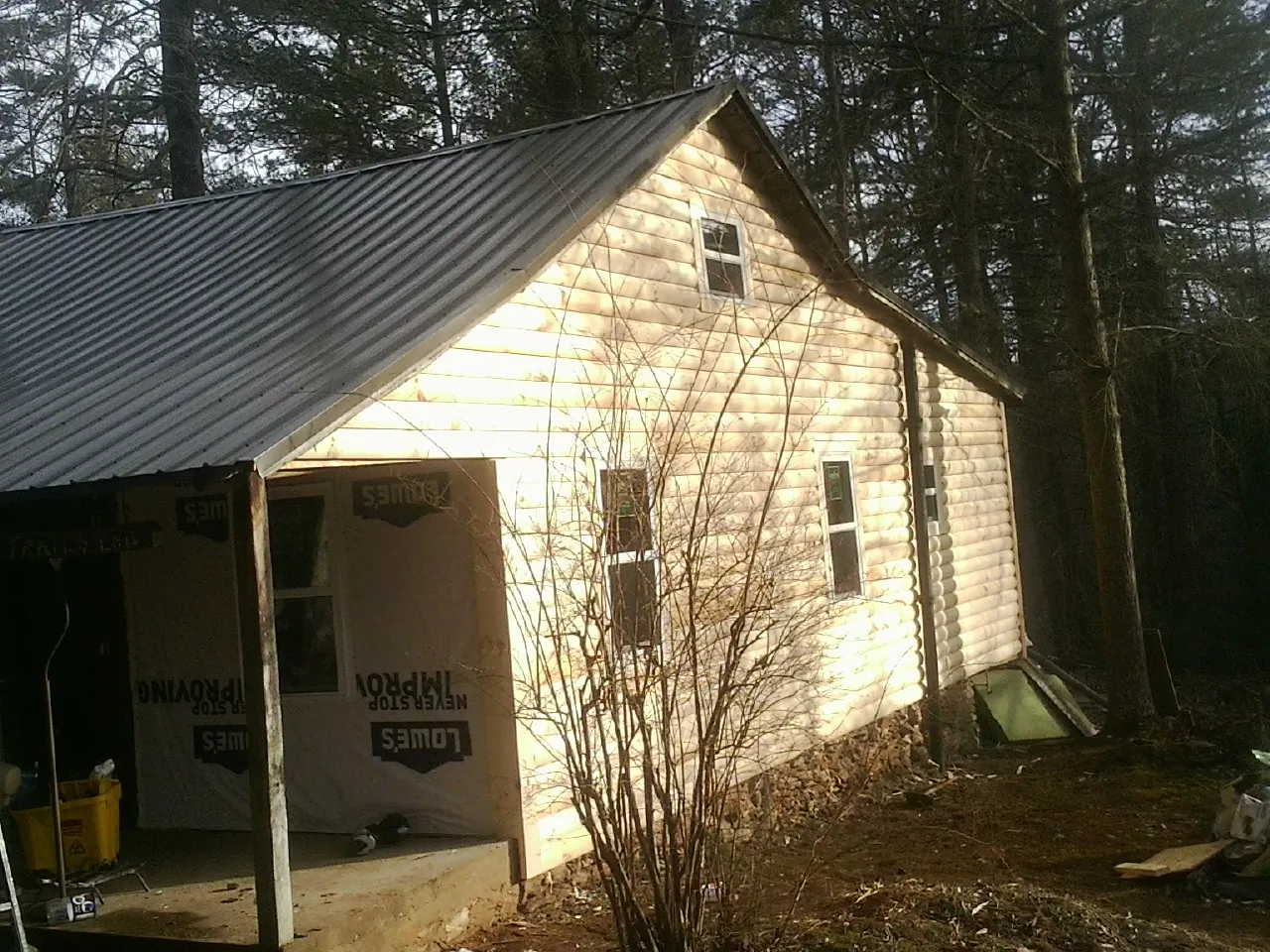 Log siding gable end under a dark metal roof edge in Bulverde