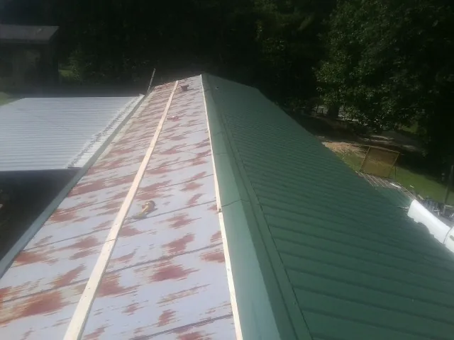 Old rusted panels beside newly installed green metal roofing — Wind Damage Roof Repair by Roofing Brothers in Bulverde