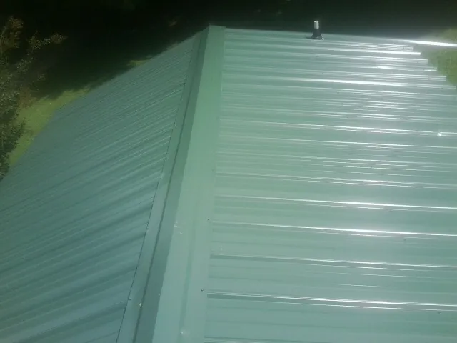 New green metal panels meeting at the ridge of a roof — Flat Roof Repair work by our crew in Bulverde