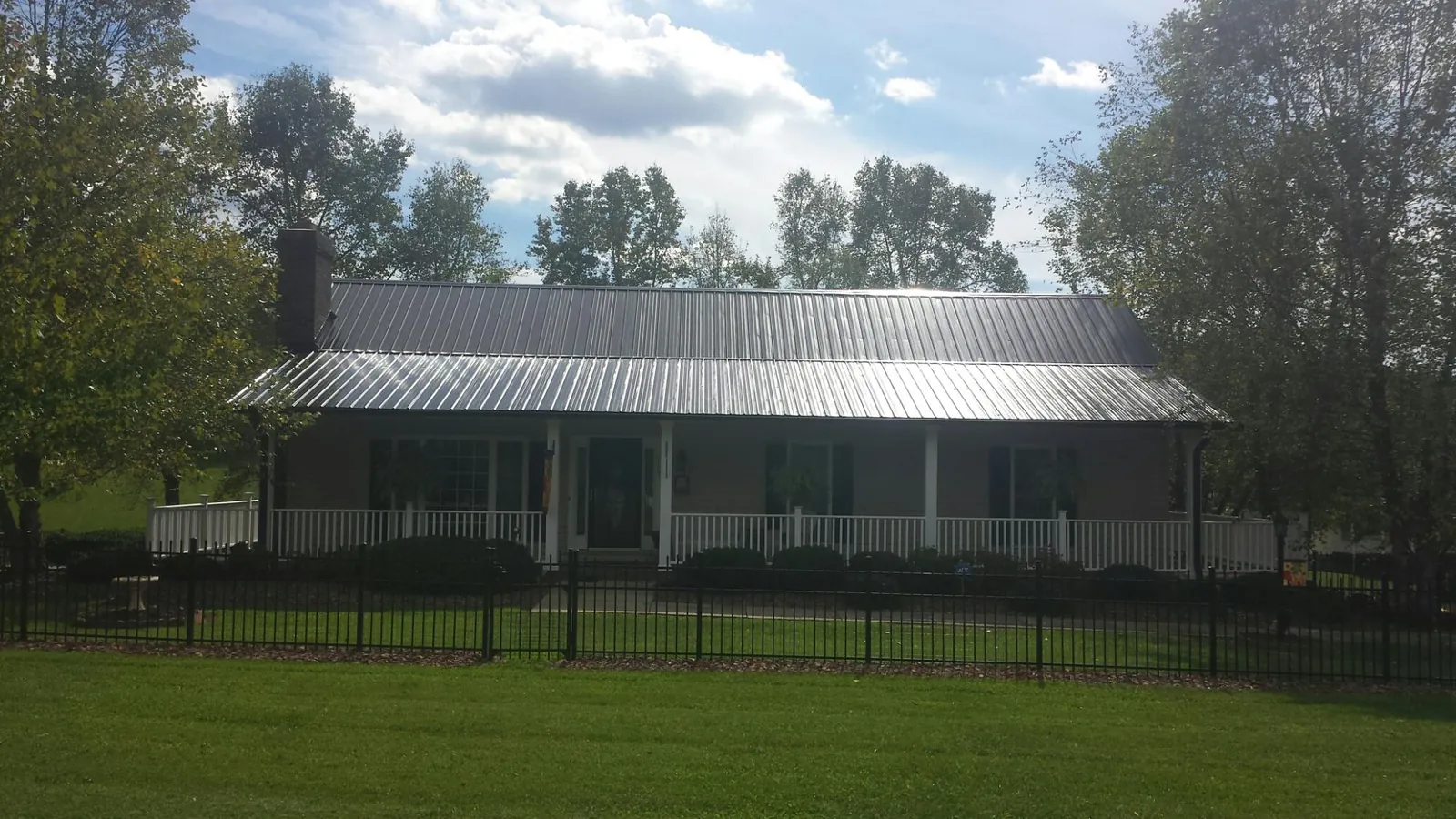 Gray metal roof on a brick ranch with a full width front porch — Gutter Guard Installation work by our crew in Bulverde